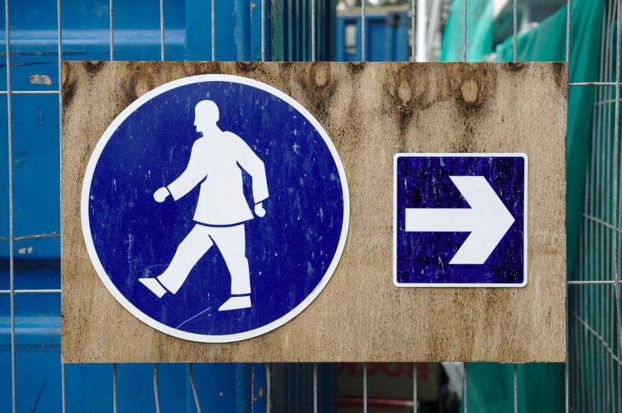 Bord met pijl en voetganger die in tegengestelde richting wijzen.