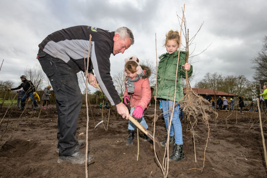 Hovenier en kinderen werken samen aan planten bomen voor een Tiny Forest in Oss