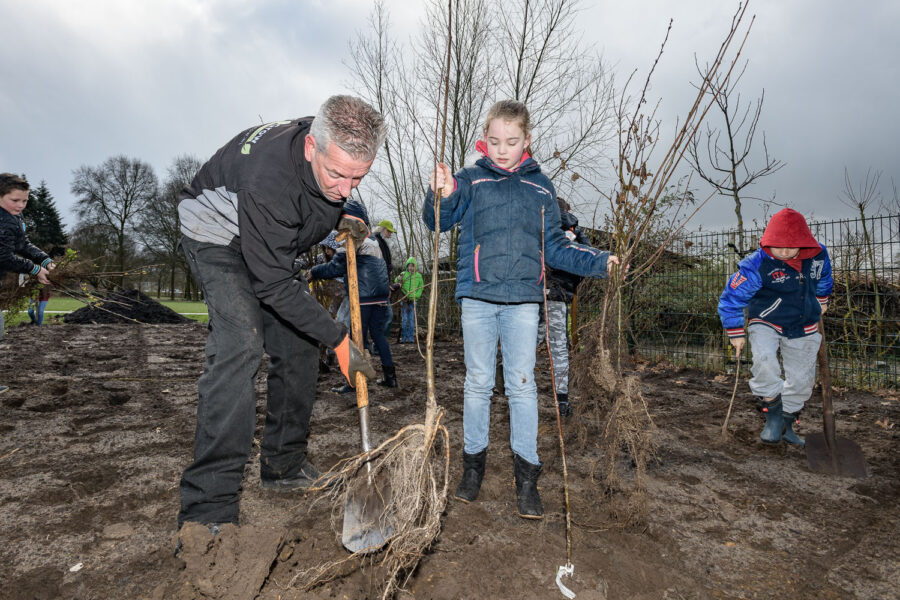 Hovenier en kinderen werken samen aan planten bomen voor een Tiny Forest in Oss